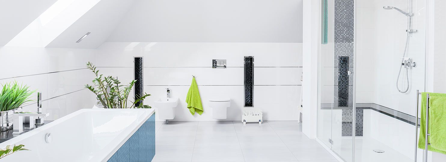 Ein modernes Badezimmer mit grünen Details - weiße Sanitäranlagen stehen breitgefächert im großen Raum